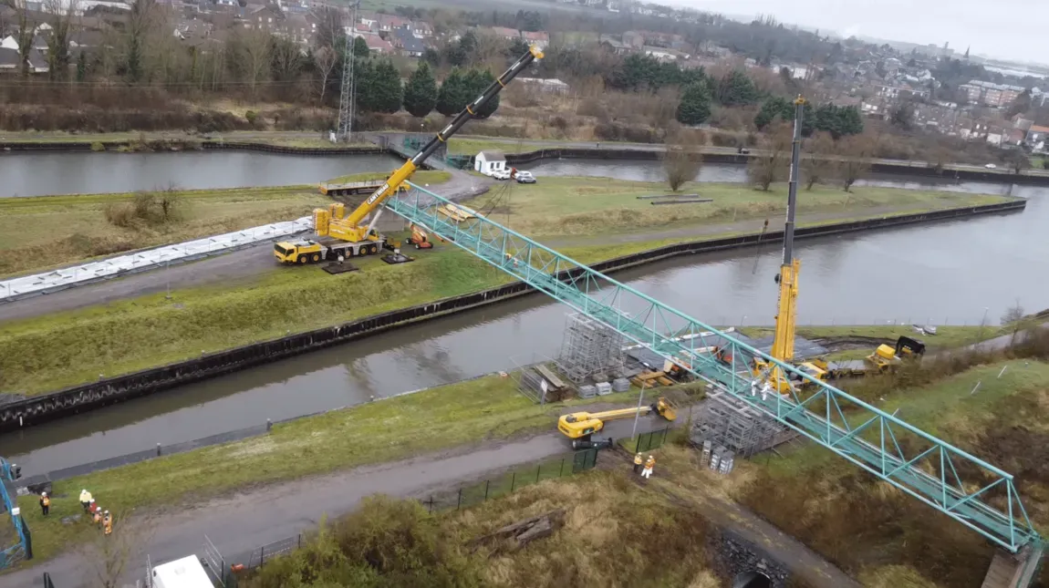 Deux grues Cantiniau positionnent une passerelle métallique au-dessus d’un canal