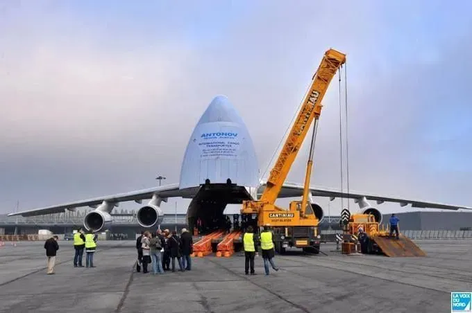 Grue et équipe devant un avion cargo